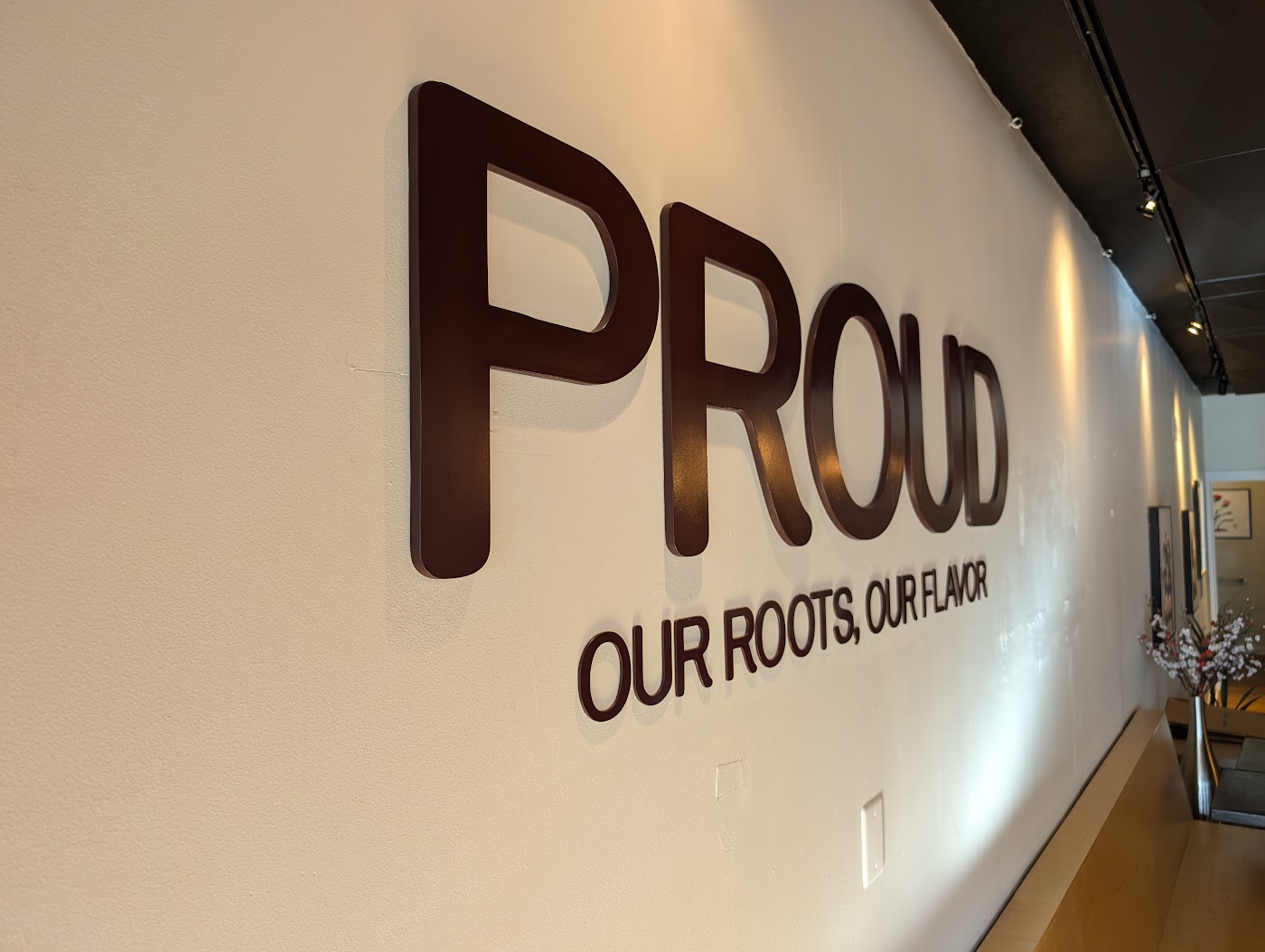 Dimensional metal lobby sign with large and small letters on a white wall in Portland, OR.