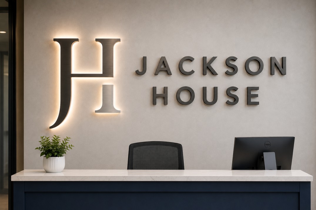 Illuminated dimensional lobby sign behind reception desk for modern Portland office branding