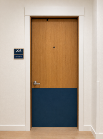 ADA-compliant braille room sign mounted beside a bedroom door, featuring room number and name on a navy-blue plaque with tactile lettering and braille for accessibility and wayfinding.